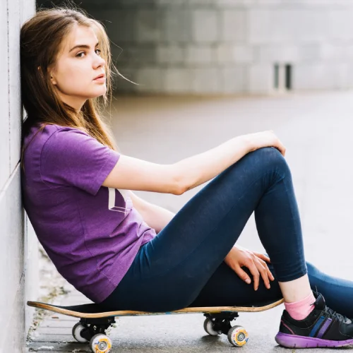adolescente sobre su skateboard pensando junto a la pared